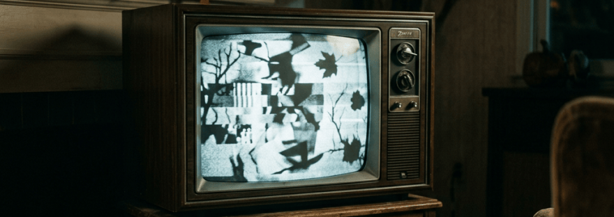 Vintage television showing static beside a candlelit fireplace and armchair